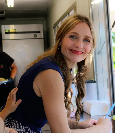 A volunteer leaning out of the food truck window, smiling