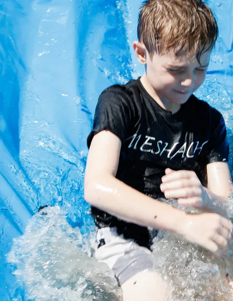 A boy coming down the water slide at the church family day